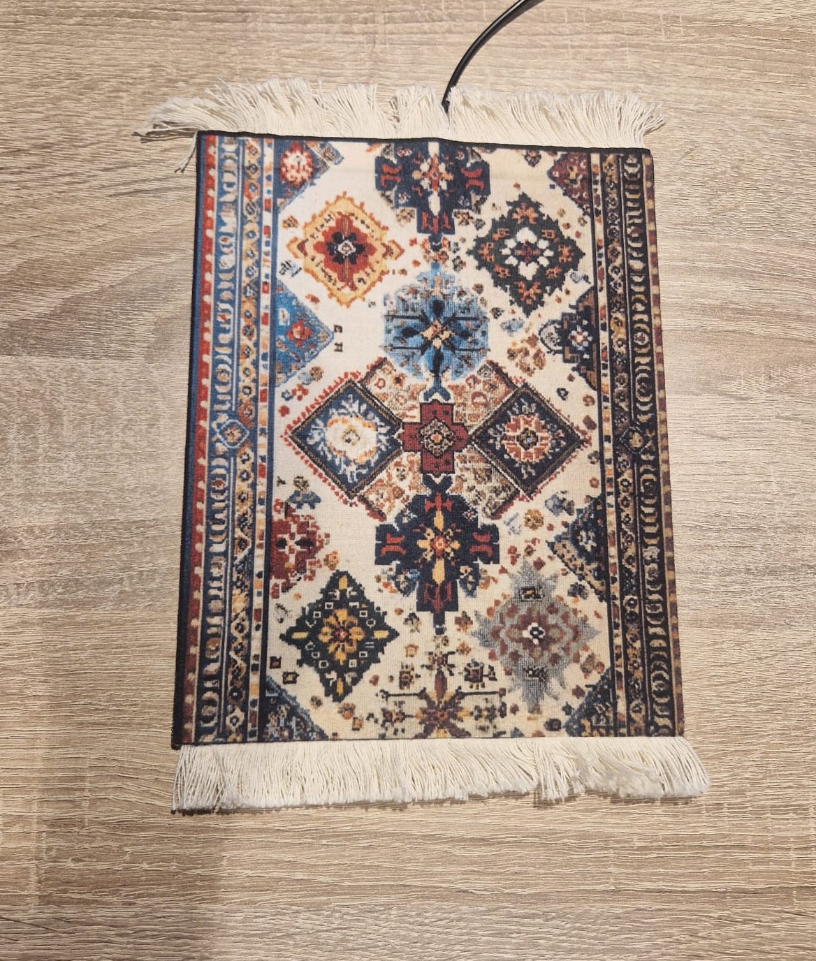Voorbeeld van stylingadvies: verwarmde muismat met Mozaïek-dessin op een lichte eikenhouten werkplek, met de USB-kabel zichtbaar